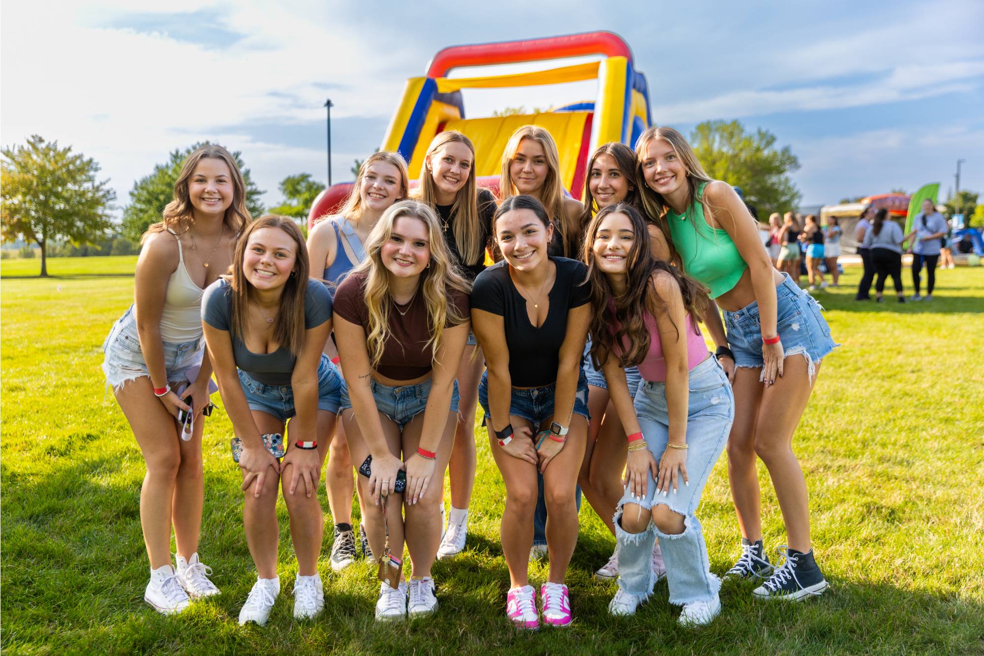 a group of female presenting students posing in front of a large inflatable obstacle course